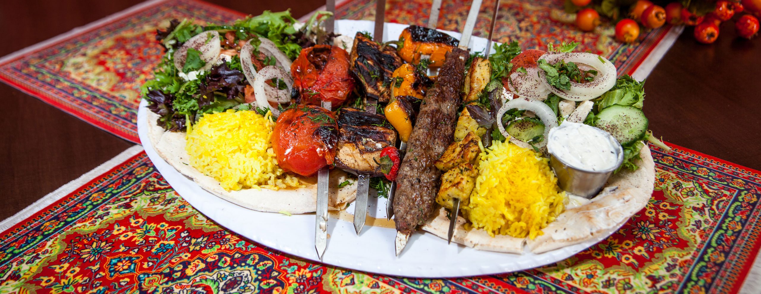 A platter of Caspian Grill food including kabobs, rice, salad, and pita.