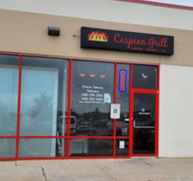 The front door of Caspian Grill's Gammon Road location, which is a simple red storefront door set inside an unremarkable beige wall in a strip mall